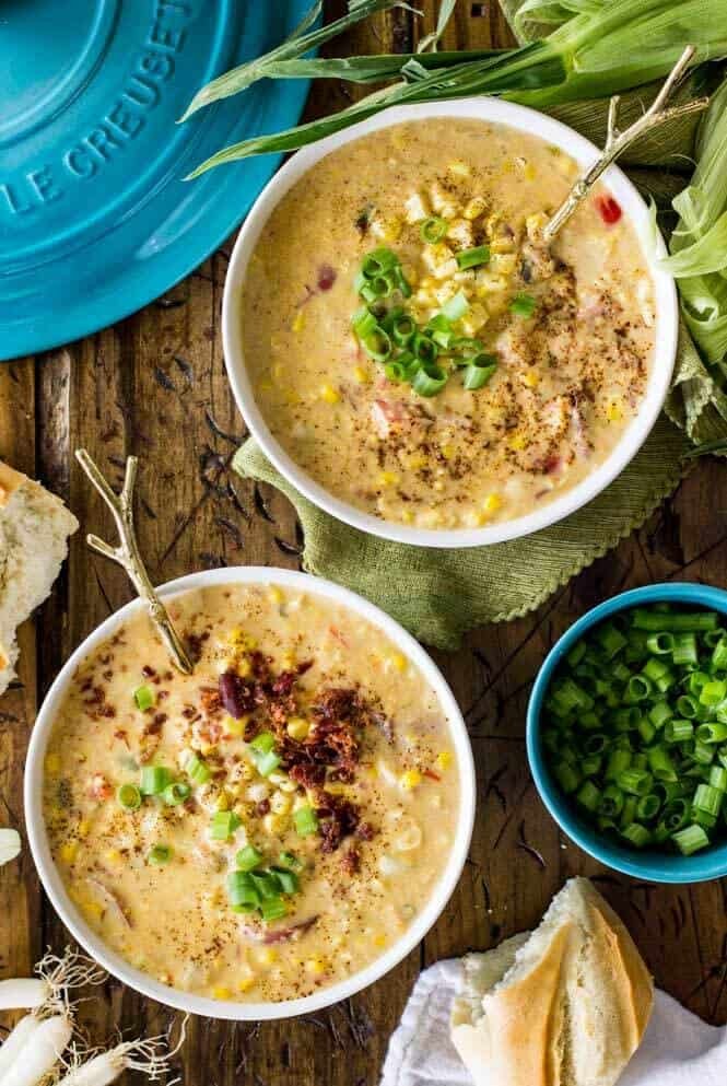 SUMMER CORN CHOWDER! A simple, hearty summer soup! #cornchowder #summerrecipe #sugarspunrun Two bowls of summer corn chowder garnished with chives and bacon