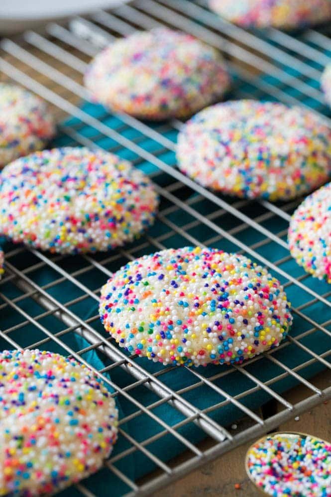 Fun, colorful, SPRINKLE COOKIES! Buttery chewy cookies encased in a colorful sprinkle shell! #cookierecipe #bestcookies Sprinkle cookies cooling on cooling rack