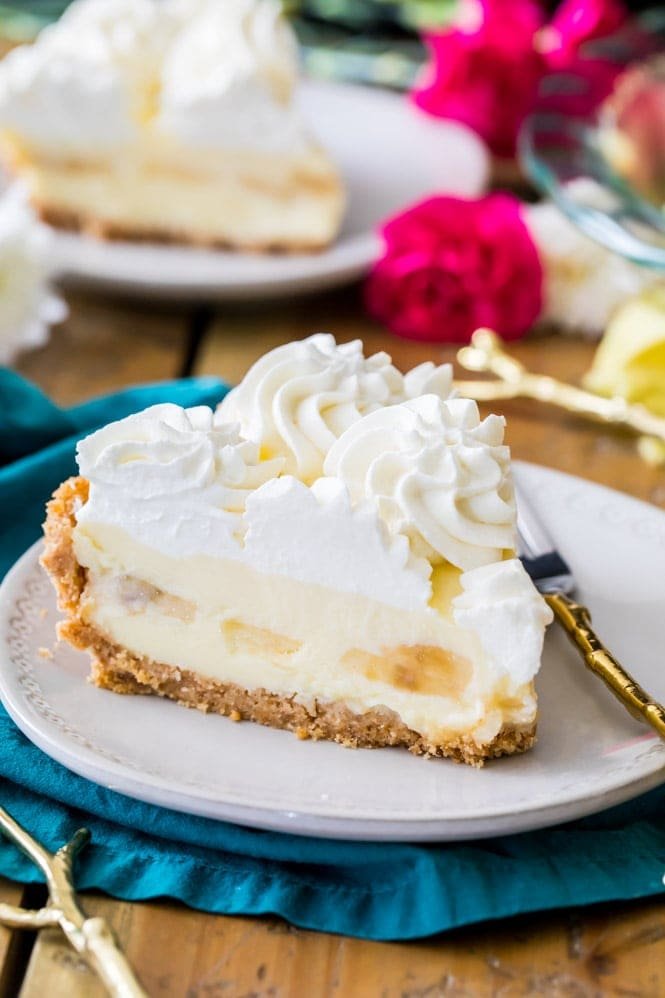 How to make the perfect BANANA CREAM PIE RECIPE. This is a simple and classic pie recipe! #pierecipe #bananacreampie #sugarspunrun Slice of banana cream pie with whipped cream on white plate