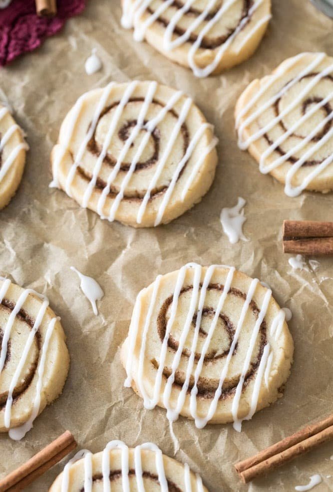 These CINNAMON ROLL COOKIES are absolutely adorable and so simple to make! Buttery, soft, filled with cinnamon sugar and drizzled with a vanilla glaze, it's everything you love about cinnamon rolls only in cookie form! #cinnamonroll #cookierecipe #christmascookie #sugarspunrun Freshly baked cinnamon roll cookies decorated with white vanilla glaze