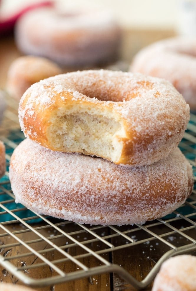 How to make HOMEMADE DONUTS! This recipe for yeasted donuts makes soft, fluffy donuts in under 2 hours. A how-to VIDEO is included! #sugarspunrun #donuts #donutrecipe #yeastrecipe Homemade donut with a bite out of it, showing the soft fluffy interior