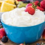 Fruit dip in a blue bowl with strawberries in it.