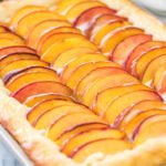 Close-up view of peach cake topped with sliced peaches in jellyroll pan