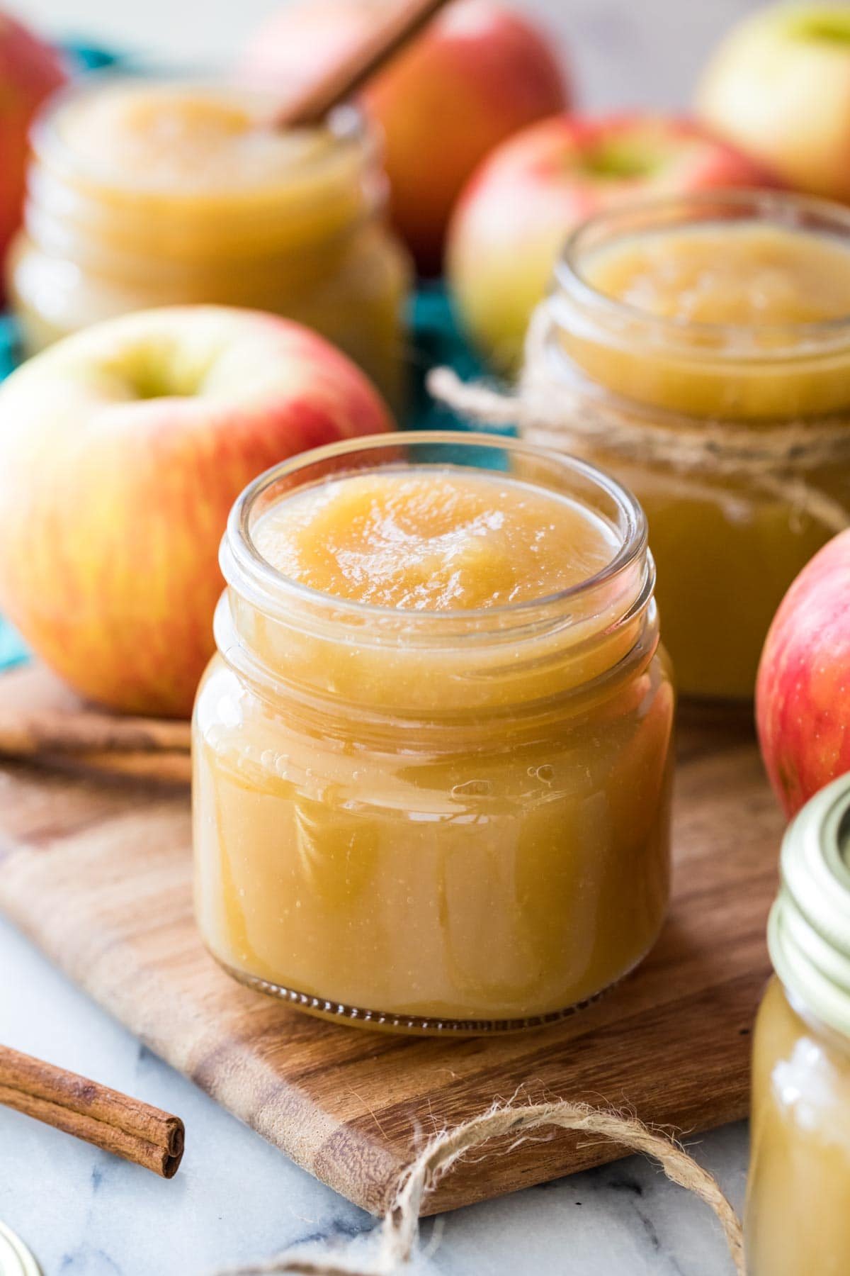 Clear glass jars filled with golden colored applesauce from my applesauce recipe with red apples intermingled