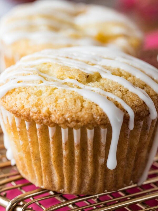 Peach muffins drizzled with vanilla glaze on a cooling rack.