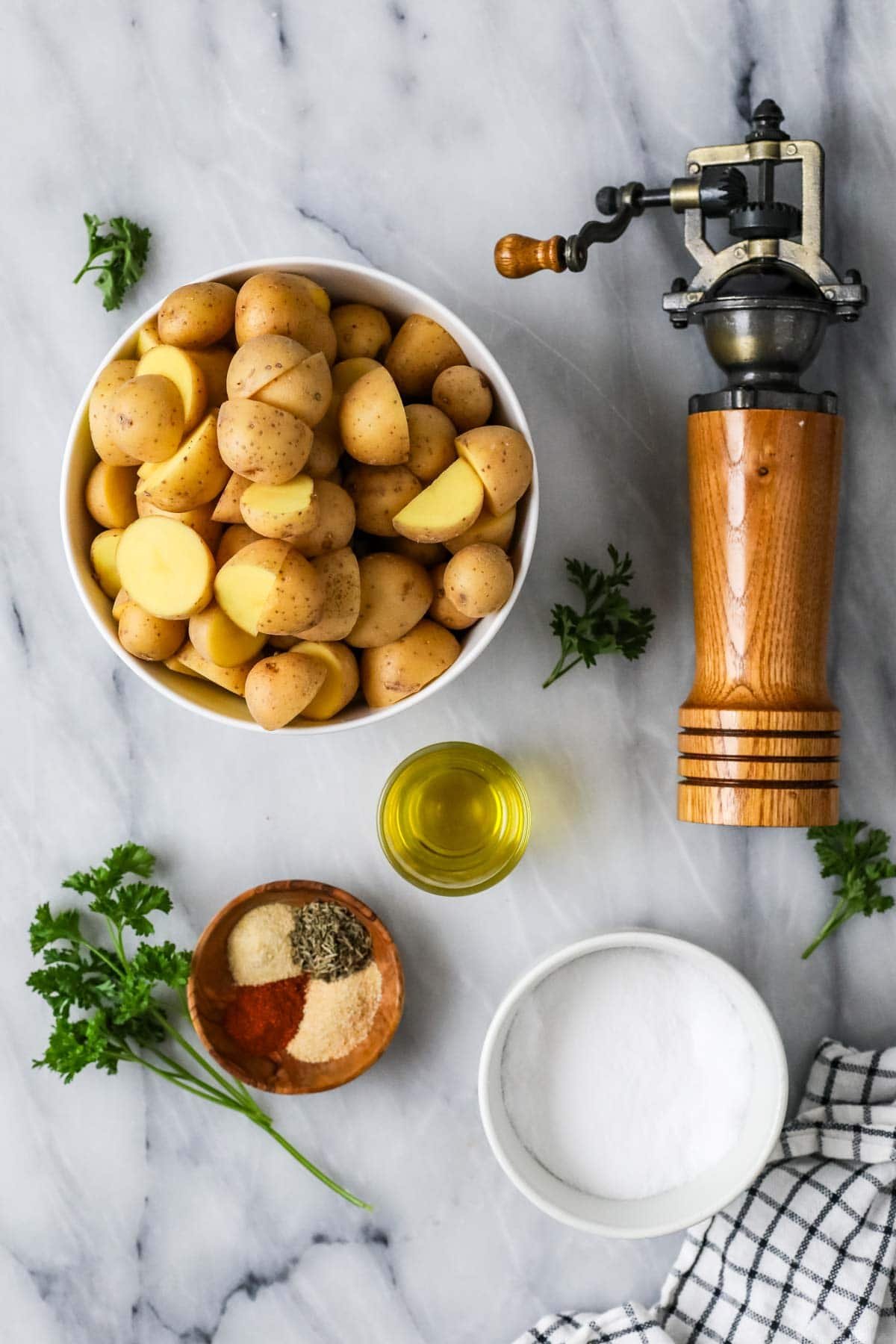 Overhead view of ingredients including potatoes, olive oil, spices, and fresh parsley.