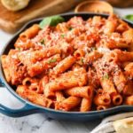 Skillet of homemade rigatoni topped with freshly grated parmesan cheese.