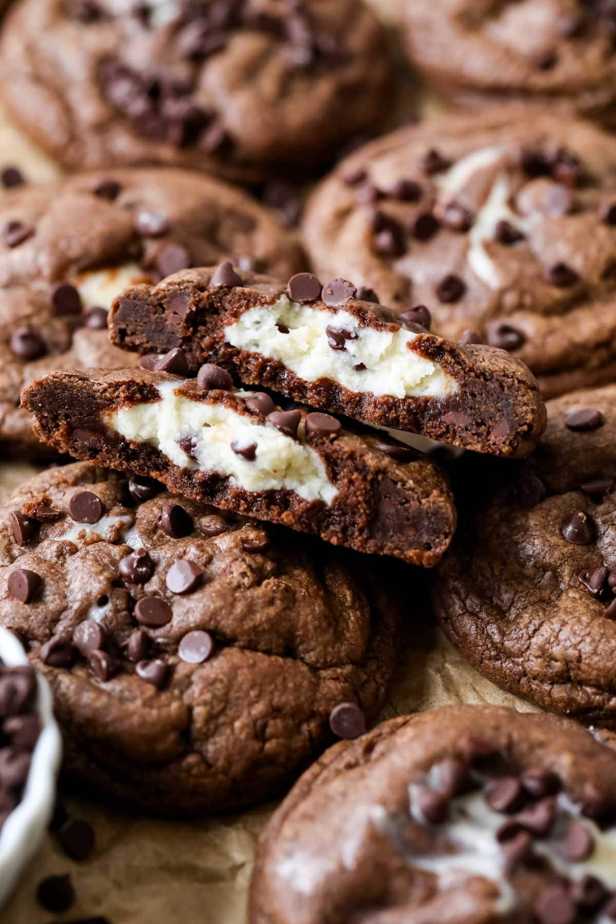 Arrangement of black bottom cookies with the center cookie broken in half showing a cream cheese center.