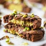 Two stacked halves of a Dubai chocolate cookie filled with pistachio cream and kataifi.
