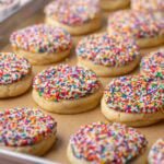 Close-up of dot cake cookies in a parchment lined baking sheet.