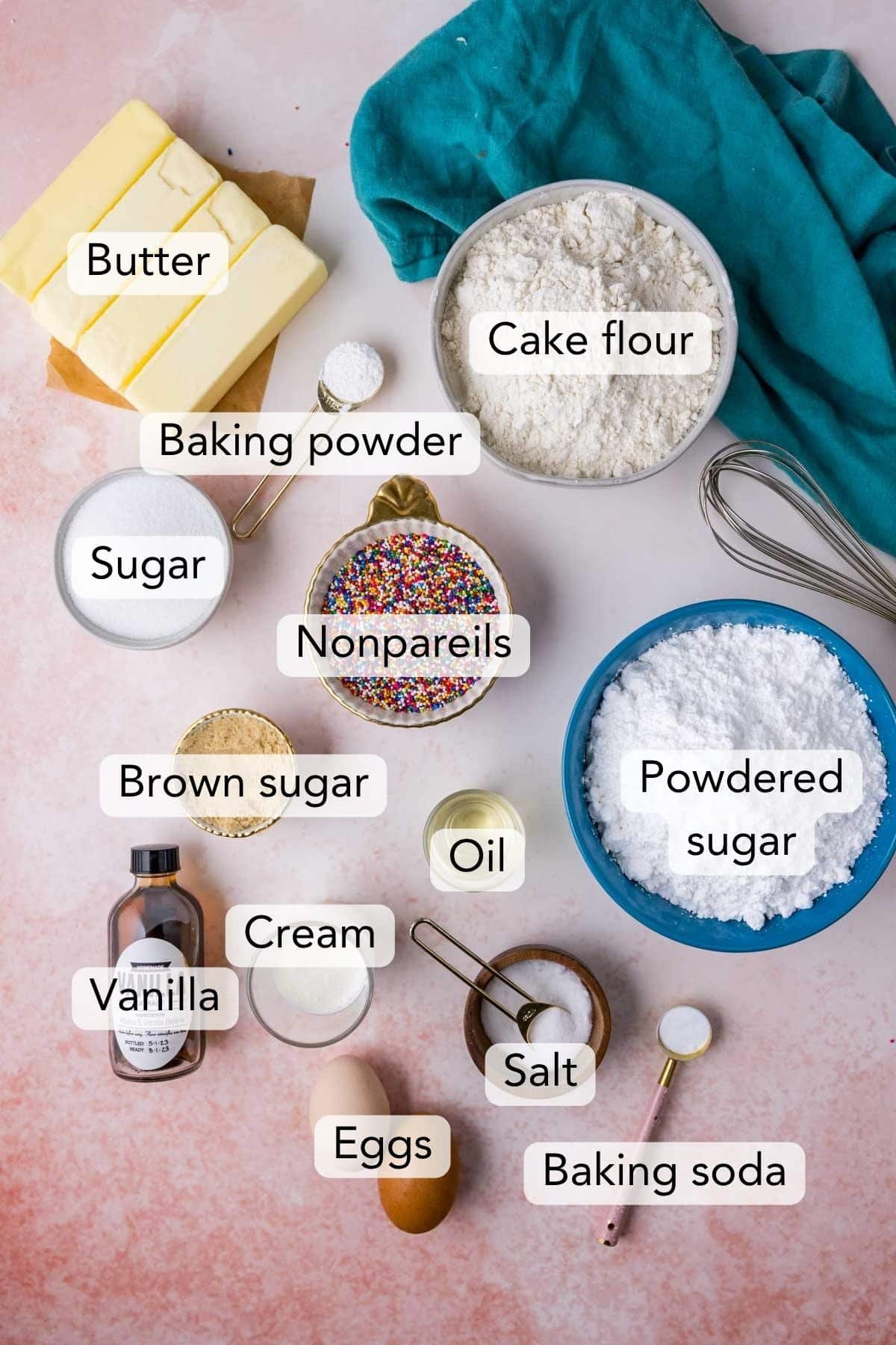 Overhead view of ingredients including cake flour, nonpareils, vanilla extract, and more.