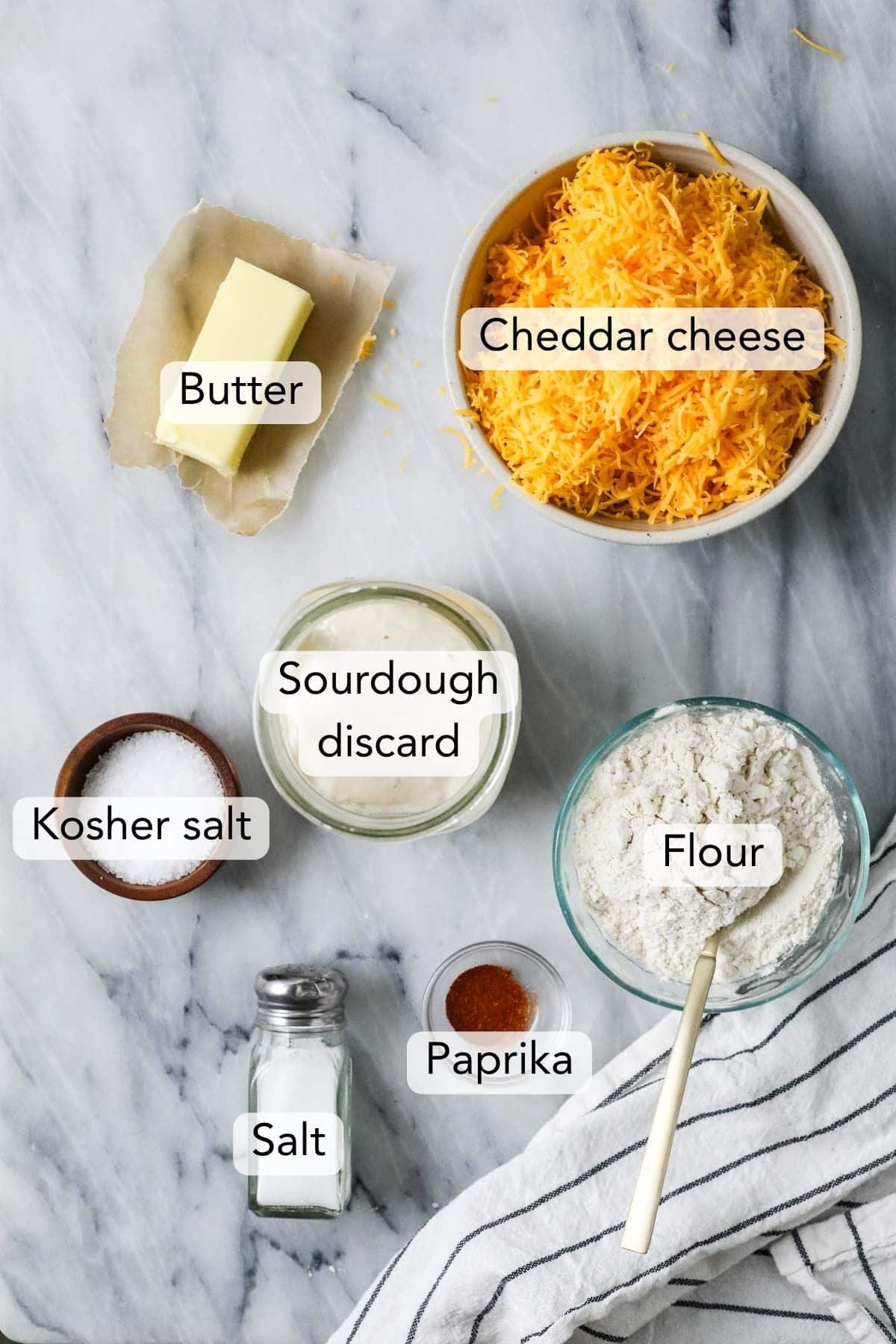 Overhead view of ingredients including shredded cheddar, butter, sourdough discard, and more.