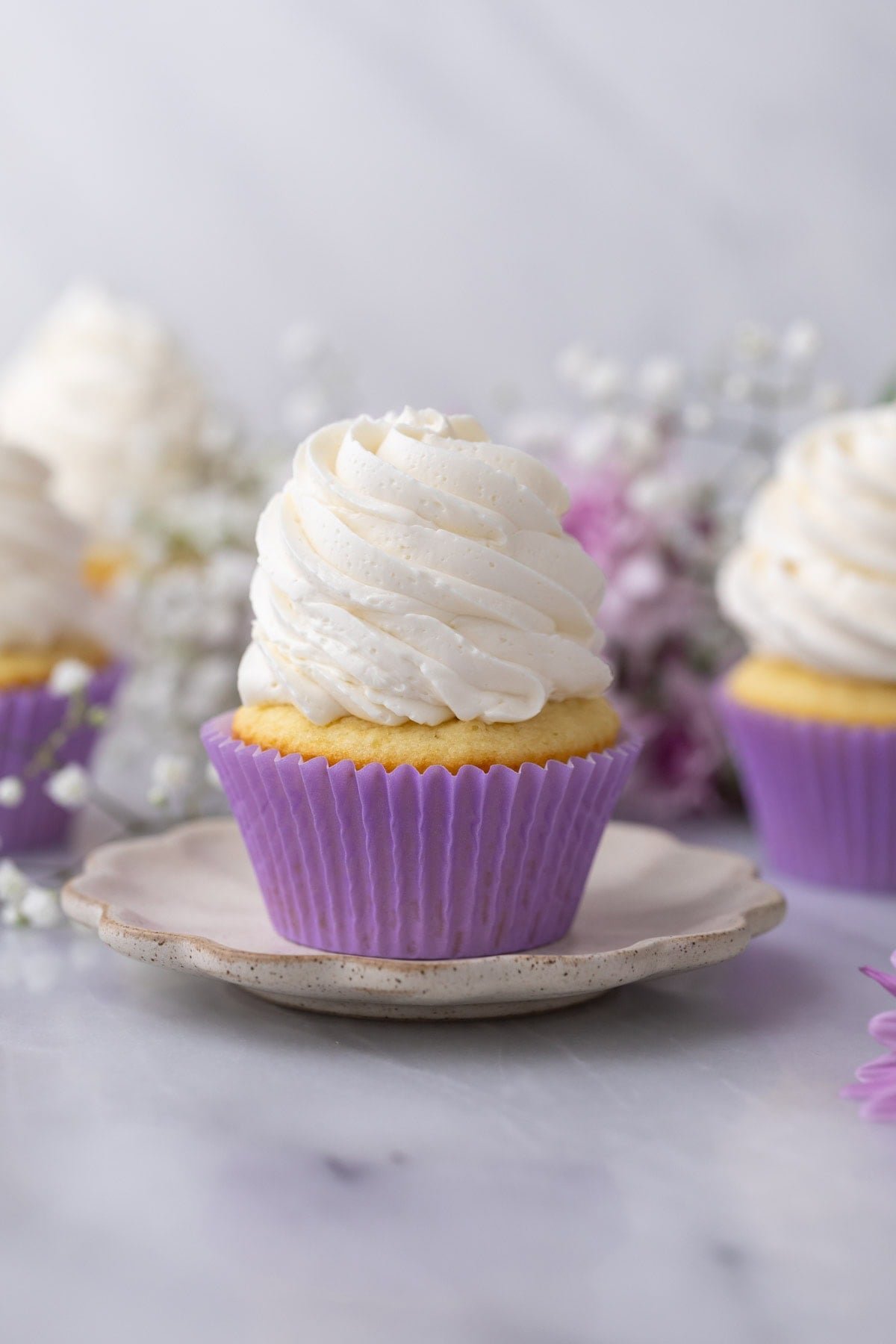 Cupcake topped with a tall swirl of swiss meringue buttercream frosting.
